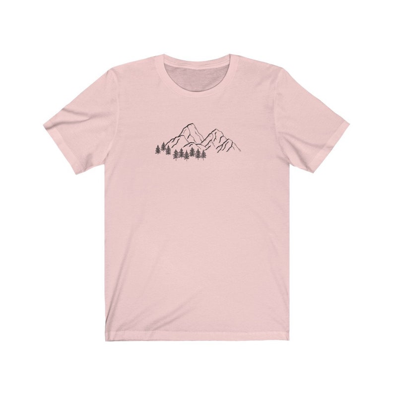 May include: A pink short-sleeved t-shirt with a black line drawing of mountains and trees on the front.