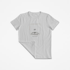 Peut inclure: Un t-shirt gris clair avec un motif graphique de montagnes et un soleil avec le texte "GO OUTSIDE" dans un cadre.