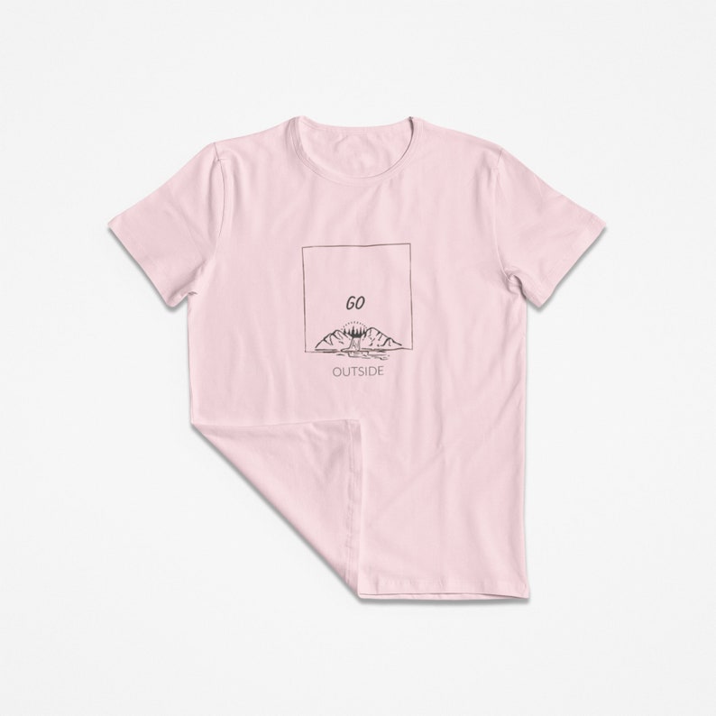 Peut inclure: T-shirt rose avec un graphique noir de montagnes et un soleil avec le texte "GO OUTSIDE" dans un encadr&eacute;.