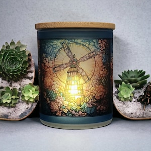 May include: A ceramic candle jar with a bamboo lid features a colorful illustration of a windmill with a glowing light inside. The jar has a blue base and a blue rim.