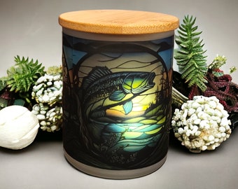 Può includere: Un barattolo di vetro per candele con un coperchio in bambù presenta un design in vetro colorato di un pesce che salta fuori dall'acqua. Il design include sfumature di blu, verde, giallo e arancione.