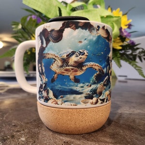 May include: White ceramic coffee mug with a cork base. The mug features a colorful image of a sea turtle swimming in the ocean with coral and seashells.