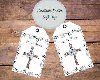 Puede incluir: Dos etiquetas de regalo de Pascua imprimibles con una cruz y un diseño floral de acuarela. El texto en las etiquetas dice "Ha resucitado".