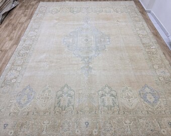 May include: Large beige area rug with a central medallion design in light blue and green. The rug features an intricate border and overall distressed appearance, suitable for living rooms or bedrooms.