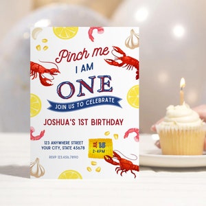 May include: A birthday invitation with a red and blue colour scheme featuring a lobster, lemons, garlic, and corn. The text reads "Pinch me I am one. Join us to celebrate Joshua's 1st Birthday. 123 Anywhere Street, Your City, State 45678. RSVP 123.456.7890. 1-15 2-4PM."