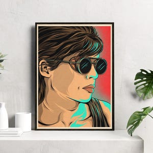 May include: A digital illustration of a woman with short brown hair wearing large, round, black goggles with a teal frame. The woman is looking to the right and has a serious expression on her face. The background is a red and orange gradient.
