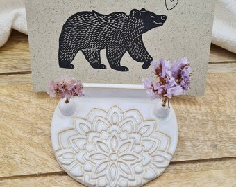 Könnte beinhalten: Ein weißer Keramik-Kartenhalter mit Mandala-Design und zwei kleinen Vasen. Eine Karte mit einer Schwarzweiß-Illustration eines Bären mit einem Herzen darüber wird im Halter angezeigt.