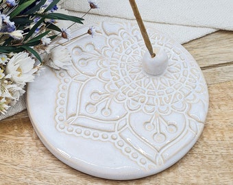 May include: White ceramic incense holder with a detailed mandala design. The holder has a small hole in the center for incense sticks.
