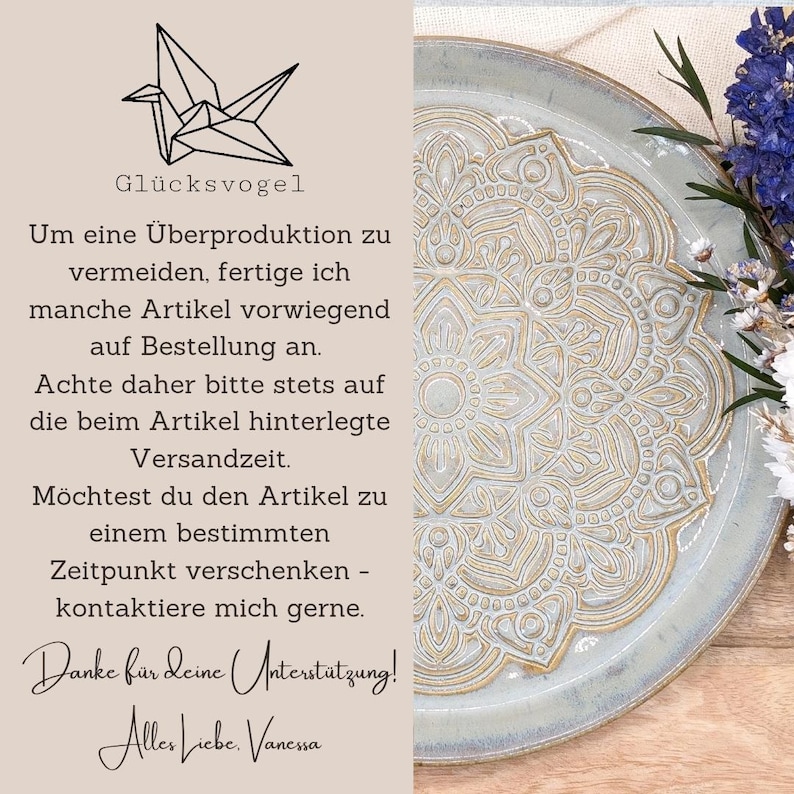 May include: A ceramic plate with a detailed gold mandala design on a light blue background. The plate is surrounded by dried flowers and text in German, including "Gl&uuml;cksvogel" and a message about made-to-order items.