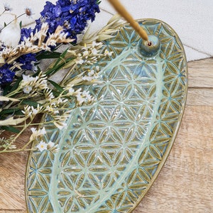 Könnte beinhalten: Ein grüner Keramik-Räucherofen mit geometrischem Muster. Der Räucherofen ist oval geformt und hat ein kleines Loch in der Mitte für Räucherstäbchen.