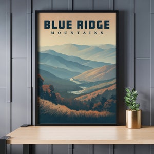 May include: Framed art print depicting the Blue Ridge Mountains. The artwork shows a scenic view of layered mountain ranges in shades of blue, green, and gold, with the text "BLUE RIDGE MOUNTAINS" at the top. The print is in a black frame.