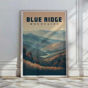 May include: A framed art print depicting the Blue Ridge Mountains. The image shows layers of blue and brown mountain ranges beneath an orange sky. The words "BLUE RIDGE MOUNTAINS" are printed at the top of the artwork.