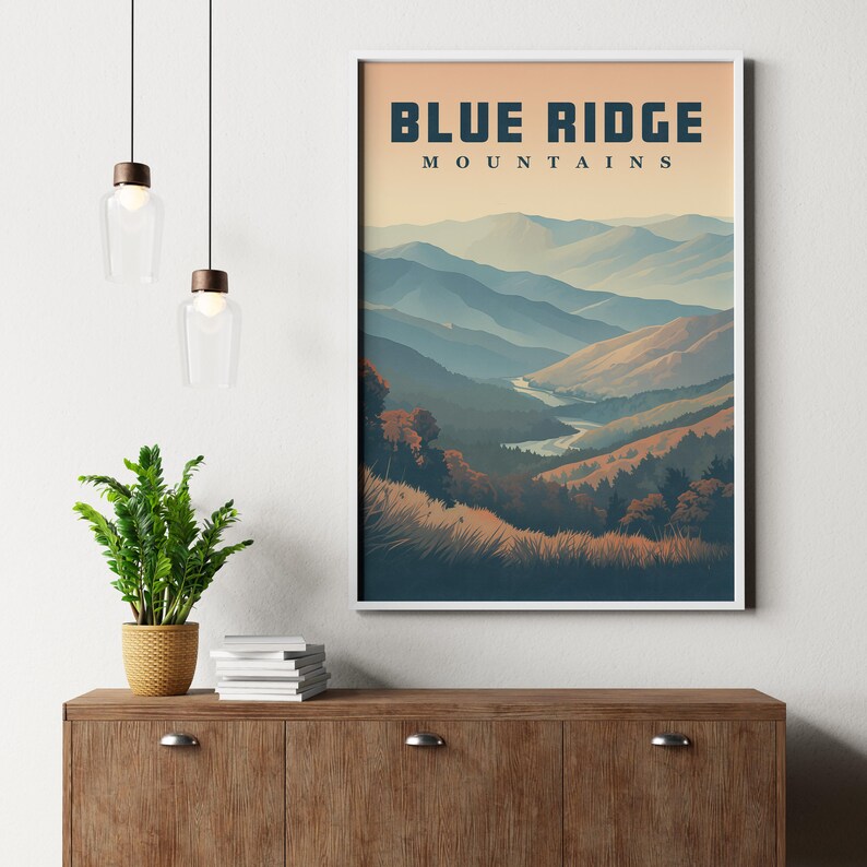 May include: A framed print depicting the Blue Ridge Mountains. The artwork shows a landscape of hills and a river, with the text "BLUE RIDGE MOUNTAINS" at the top. The colour scheme includes blues, greens, and earth tones, creating a serene mountain scene.