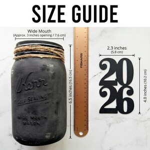 May include: A white ceramic mug with a black handle and the text "But First, Coffee" in a black, bold font. The mug is on a white surface.