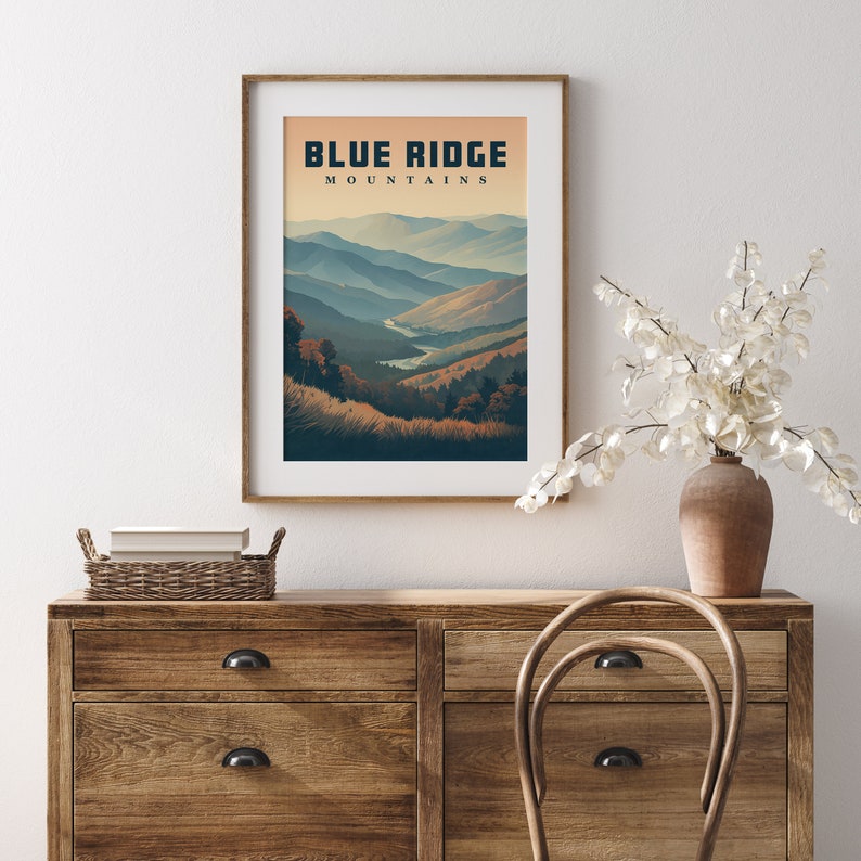 May include: A framed art print depicting the Blue Ridge Mountains. The image shows a layered landscape of blue and tan mountains under a warm sky. The words "BLUE RIDGE MOUNTAINS" are printed at the top of the artwork.