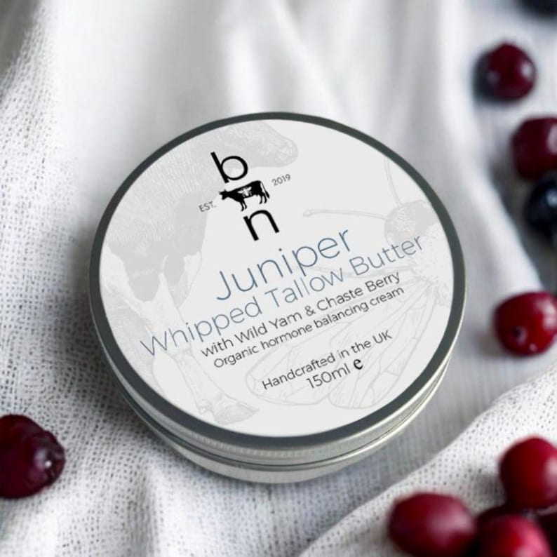 May include: A silver tin of Juniper Whipped Tallow Butter with a white label. The label features a cow illustration, the text "EST. 2019", and the brand name "b n". The product description reads "Juniper Whipped Tallow Butter with Wild Yam & Chaste Berry Organic hormone balancing cream Handcrafted in the UK 150ml e".