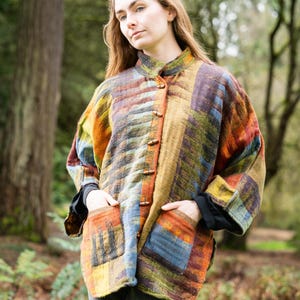 May include: A long-sleeved jacket featuring a multi-colored woven pattern in shades of orange, yellow, blue, and green. The jacket has a high collar, a front closure with wooden toggle buttons, and two large patch pockets on the front lower section.