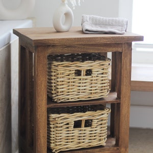 Könnte beinhalten: Ein Holzregal mit zwei geflochtenen Körben. Das Regal ist dunkelbraun gebeizt und hat ein schlichtes Design. Die Körbe sind aus natürlichem Weidengeflecht und haben eine rechteckige Form.