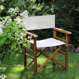 Può includere: Una sedia da regista pieghevole realizzata in legno marrone con seduta e schienale in tessuto bianco. La sedia presenta una struttura a gambe incrociate con braccioli e un pannello posteriore rettangolare, offrendo una seduta stabile.