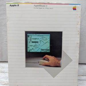 May include: Vintage Apple II AppleMouse II box. The box is white with the Apple logo and product information. The image on the box shows a computer screen with the AppleMouse interface and a hand using the mouse.