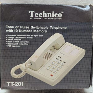 May include: A vintage Technico TT-201 telephone in its original box. The off-white phone features a keypad, handset, and coiled cord. The box displays the Technico logo and product features, including tone/pulse switchable and 10 number memory.