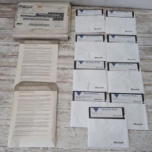 May include: A collection of Microsoft Works software, including several 3.5-inch floppy disks in white sleeves, a packing list, and printed documentation. The disks and packaging feature the Microsoft logo.