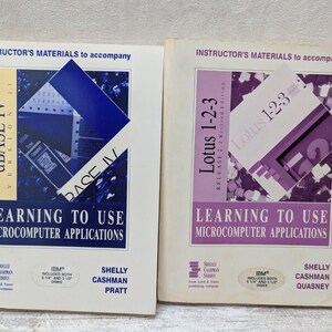May include: Two vintage computer software manuals titled "dBASE IV" and "Lotus 1-2-3". The manuals are white with blue and purple accents, and feature the text "Learning to Use Microcomputer Applications". The books are from the Shelly Cashman Series.