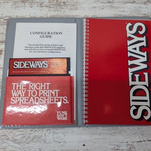 May include: An open binder with a red cover and the word "SIDEWAYS" in white. Inside, a configuration guide and a red envelope with the text "THE RIGHT WAY TO PRINT SPREADSHEETS" are visible. A 3.5-inch floppy disk is also present.