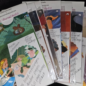 May include: A stack of colorful cards with images of Disney characters and the text "VHS Journal Refill Package" written on them. The cards are labeled with different types of pages, including lined, divider, and full page Disney pocket.