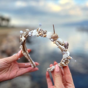 May include: A white headband decorated with seashells and pearls. The headband is made of natural materials and has a rustic look.