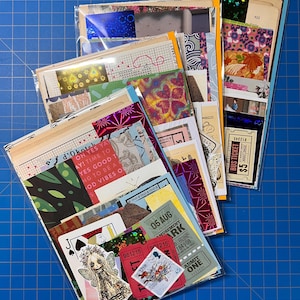May include: A collection of four clear plastic sleeves filled with assorted paper ephemera, including vintage-style bus tickets, playing cards, holographic foil accents, floral patterns, grid paper, and a small illustration of a fairy-like figure.