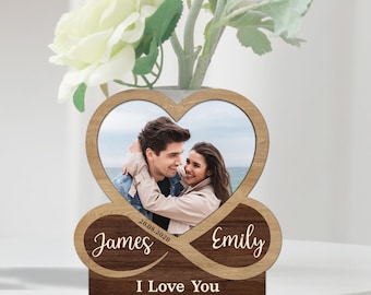 May include: Wooden heart-shaped photo frame with a couple's photo inside. The frame is decorated with an infinity symbol and the names "James" and "Emily" with the date "20.08.2020". The text "I Love You" is inscribed below the infinity symbol.