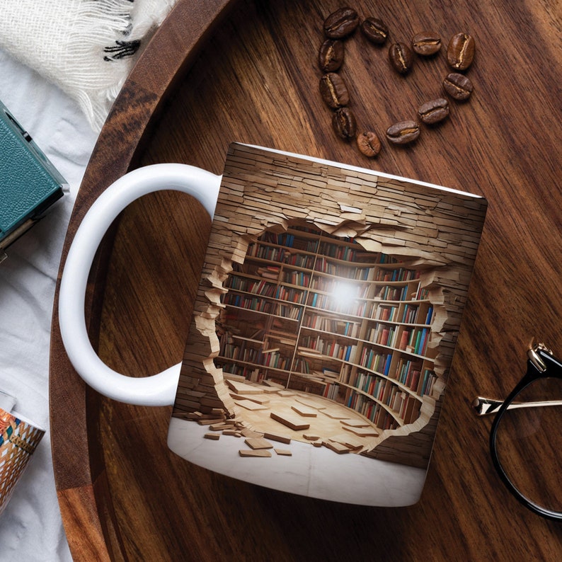 K&ouml;nnte beinhalten: Wei&szlig;e Keramiktasse mit einem Design einer Backsteinmauer mit einem Loch, das zu einer Bibliothek mit B&uuml;cherregalen f&uuml;hrt, die mit B&uuml;chern gef&uuml;llt sind. Die Bibliothek wird von einer einzigen Gl&uuml;hbirne beleuchtet.
