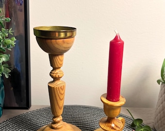 May include: Two wooden candle holders, one with a brass top and the other with a simple design. Both are made of light wood with a natural finish.
