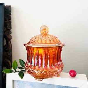 May include: A vintage amber glass candy dish with a lid. The dish has a fluted design and a scalloped edge. The lid has a knob on top.