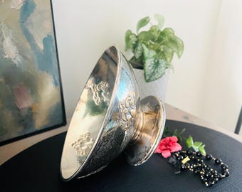 May include: A silver bowl with an ornate design and a gold base. The bowl is sitting on a black surface.