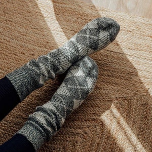 May include: A pair of cosy, grey and white patterned socks with a diamond pattern. The socks are made of a soft, warm material and are perfect for keeping your feet warm in the winter.