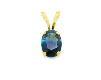 May include: A gold pendant featuring an oval, deep blue gemstone. The gemstone is set in a gold bezel with a gold bail. The pendant is displayed against a white background, highlighting the jewelry's design and color.