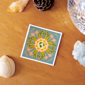 May include: A blue square sticker with a floral design and a globe in the center. The text "Care for our Earth" is written around the globe.