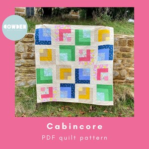 May include: A colorful quilt with a patchwork design, featuring squares of various colors including blue, green, yellow, and pink. The quilt is displayed outdoors against a stone wall and grass. The text "Cabincore PDF quilt pattern" is visible.