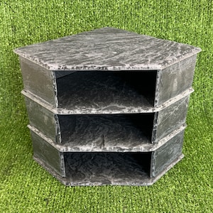 May include: A three-tiered corner shelf made of dark grey slate. The shelf has a rustic, natural look and is perfect for displaying small items.