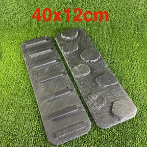 May include: Two rectangular dark grey slate boards measuring 40x12 cm. One board features six horizontal raised bars, while the other board displays six irregular, rounded, raised stone-like shapes attached to its surface.