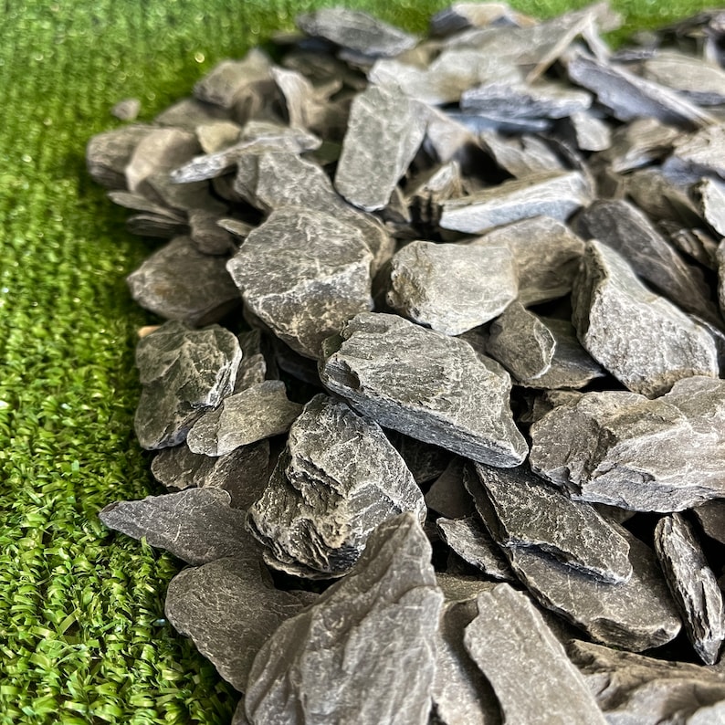 Puede incluir: Un mont&oacute;n de virutas de pizarra gris oscuro, perfectas para paisajismo o fines decorativos.