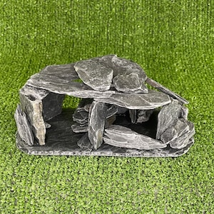 May include: A grey slate rock cave hideaway for small animals or reptiles. The cave is made of stacked slate rocks and has a natural, rustic look.
