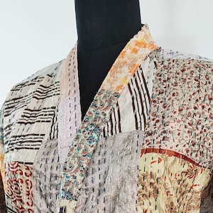 May include: A patchwork kimono robe with a variety of floral and geometric patterns in shades of brown, beige, pink, green, and purple. The robe has a sash tie and long sleeves.