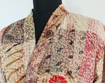 Puede incluir: Una bata de manga larga hecha de tela de patchwork en tonos beige, marrón, rosa y rojo. La bata tiene un cinturón de atar y está acolchada con puntadas intrincadas.