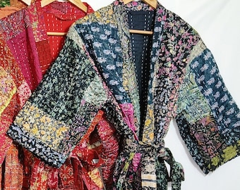 May include: Five colorful, patchwork-style robes hanging on wooden hangers. The robes feature a variety of colors including green, blue, orange, red, and black. Each robe has a matching belt. The robes are made of a quilted fabric.