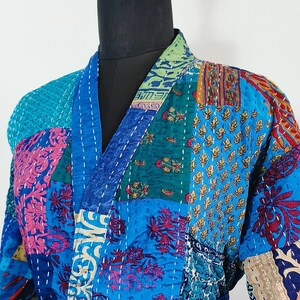 May include: A blue and multi-colored patchwork kimono robe with a sash tie. The robe is made of quilted fabric with a variety of floral and geometric patterns.