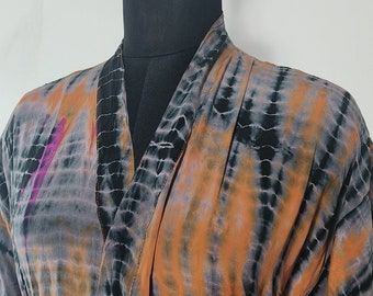 May include: A long-sleeved robe with a tie-dye pattern in shades of orange, black, and purple. The robe has a tie belt and pockets.