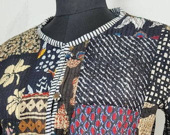 May include: A long-sleeved jacket featuring a patchwork design with various black, red, blue, and cream-colored fabric panels. The garment has a round neckline, a front button closure, and is finished with a black and white striped trim along the edges.